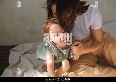 Lächelnde Frau, die auf dem Boden sitzt und mit ihrer Tochter spielt Stockfoto