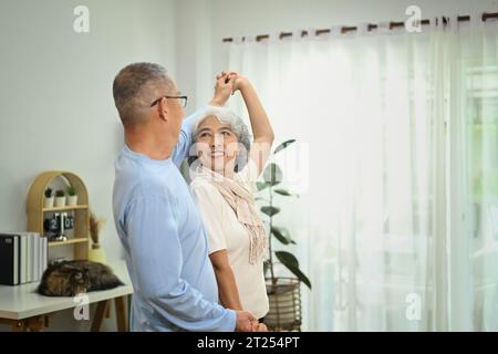 Überfröhliche ältere Rentnerin, die Spaß beim Tanzen im Wohnzimmer hatten. Lebensstil-Konzept im Ruhestand Stockfoto