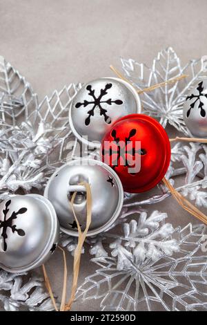 Weihnachtshintergrund mit roten und silbernen rustikalen Glocken auf Grau Stockfoto