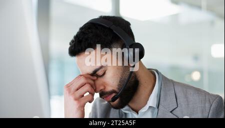 Stress, Kopfschmerzen und Mann im Callcenter, müde und müde am Helpdesk im Büro. Burnout, Angst und Vertriebsmitarbeiter im Telemarketing frustriert mit Stockfoto