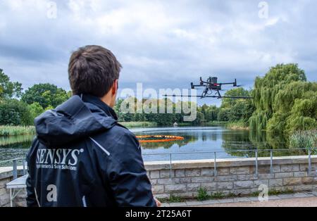 17. Oktober 2023, Mecklenburg-Vorpommern, Rostock: Eine Drohne mit Sonden zur Detektion von Magnetfeldern oder Anomalien auf dem Seeboden wird von Markus Schikorra von der Firma Sensys bei Messflügen über den Schwanenteich gesteuert. Die Aufzeichnungen können verwendet werden, um mögliche Kampfmittel im Schlamm zu identifizieren und zu lokalisieren. Da der Teich 1938 vor dem Zweiten Weltkrieg angelegt wurde, besteht der Verdacht auf eine Verseuchung mit Sprengkörpern. Foto: Jens Büttner/dpa Stockfoto