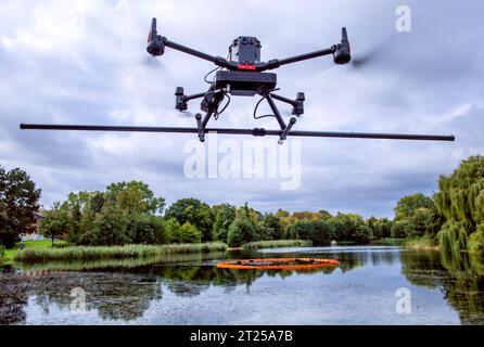 17. Oktober 2023, Mecklenburg-Vorpommern, Rostock: Eine Drohne mit Sonden zur Erkennung von Magnetfeldern oder Anomalien am Seeboden fliegt während der Messflüge über den Schwanenteich. Die Bilder können verwendet werden, um mögliche Kampfmittel im Schlamm zu identifizieren und zu lokalisieren. Da der Teich 1938 vor dem Zweiten Weltkrieg angelegt wurde, besteht der Verdacht auf eine Verseuchung mit Sprengkörpern. Foto: Jens Büttner/dpa Stockfoto