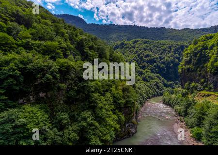 Wunderschöne Berglandschaft mit grünen Bäumen, ein Gebirgsfluss an einem sonnigen Tag mit bewölktem Himmel. Stockfoto