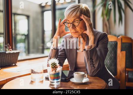 Die reife Frau sitzt in einem Café. Sie entspannt sich nach der Arbeit. Stockfoto