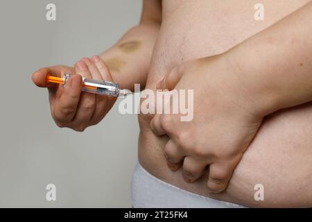 Übergewichtige Frau, die Medizin in ihre Magennaht injiziert Stockfoto