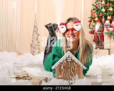 Wunderschönes Mädchen mit weihnachtsmanngläsern, die Geschenkschachtel vor einem weihnachtsbaum halten Stockfoto