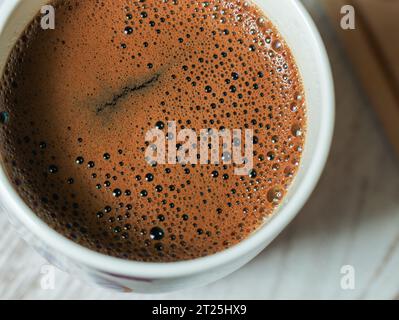 Makrobild des Kaffees in der Tasse, mit vielen Blasen oben, Nahansicht im Winkel Stockfoto
