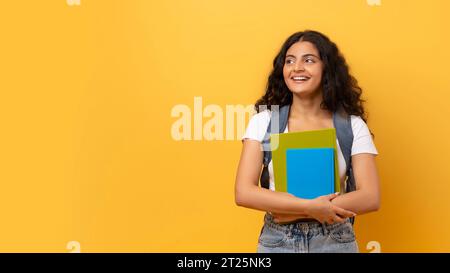 Junge lächelnde, glückliche indianerin-Studentin auf Gelb Stockfoto