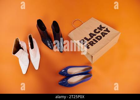 Herbstliche Stiefel und flache Schuhe in der Nähe der Einkaufstasche mit schwarzen freitag-Buchstaben auf orange, Ansicht von oben Stockfoto