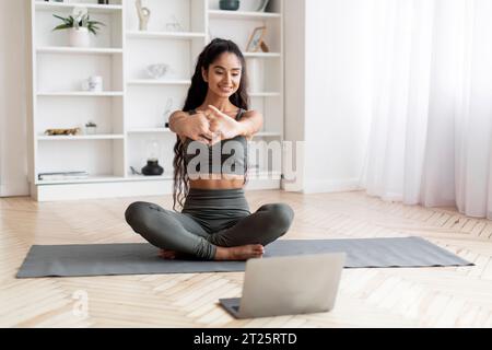 Junge Ostfrau Praktiziert Yoga Zu Hause Mit Laptop Stockfoto