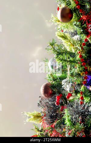 Geschmückter Weihnachtsbaum, beleuchtet durch Sonnenlicht und reflektiert an der Wand. Nahaufnahme. Vertikales Foto. Kopierbereich Stockfoto