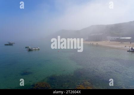 Ein Sommernachmittag und der blaue Himmel bricht durch eine Nebelbank über dem Strand und Dorf Porthdinllaen in Gwynedd, Wales Stockfoto