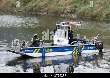 Bad Schandau, Deutschland. Oktober 2023. Tschechische Polizeibeamte fahren auf einem Boot auf der Elbe während einer Übung mit einem deutschen Schäferhund. Während der gemeinsamen Übung mit Hundehaltern und Diensthunden der tschechischen Polizei werden die Hunde auf die anspruchsvollen Einsatzsituationen im Grenzgebiet vorbereitet. Quelle: Sebastian Kahnert/dpa/Alamy Live News Stockfoto