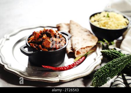 Bitteres Kürbis-Curry – Karela subji serviert mit Reis und Roti, selektiv fokussiert Stockfoto