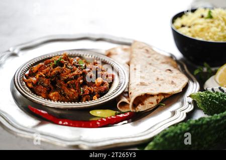 Bitteres Kürbis-Curry – Karela subji serviert mit Reis und Roti, selektiv fokussiert Stockfoto