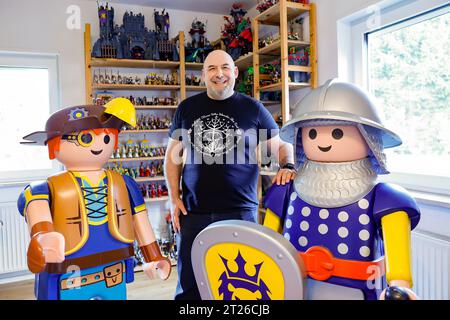 Heroldsberg, Deutschland. Oktober 2023. Stefan will zwischen zwei riesigen Playmobil-Figuren. Der Sammler hat sich seit den 1970er Jahren auf Figuren und Sets der Marke spezialisiert Darlegung: Daniel Löb/dpa/Alamy Live News Stockfoto