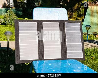 Laden einer tragbaren Solarbatterie von der Sonne auf einem Sommercampingplatz. Saubere Energie für den Einsatz im Camp. Stockfoto