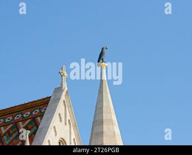 Großaufnahme des Kirchturms Matthias mit schwarzer Rabenskulptur mit vergoldetem Ring im Schnabel, Budapest, Ungarn. Stockfoto