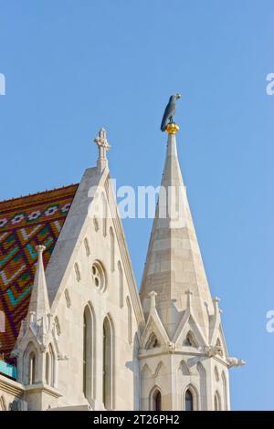 Großaufnahme des Kirchturms Matthias mit schwarzer Rabenskulptur mit vergoldetem Ring im Schnabel, Budapest, Ungarn. Stockfoto