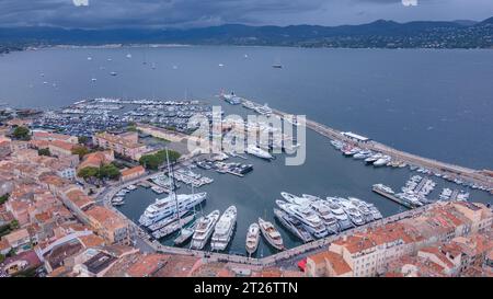 Luftaufnahme des Yachthafens in Saint-Tropez. Die Fotografie wurde von einer Drohne in einer höheren Höhe mit der Bucht im Hintergrund an einem bewölkten Tag aufgenommen. Stockfoto
