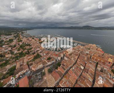 Luftaufnahme des Yachthafens in Saint-Tropez. Die Fotografie wurde von einer Drohne in einer höheren Höhe mit der Bucht im Hintergrund an einem bewölkten Tag aufgenommen. Stockfoto