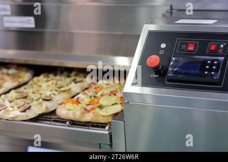 Industrieller Pizzaofen mit Förderband für Fast-Food-Restaurants. Selektiver Fokus. Stockfoto