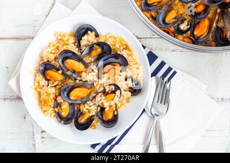 Brühe Reis mit Muscheln, gekocht mit etwas Gemüse und Weißwein, serviert in einem weißen Gericht. Draufsicht Stockfoto