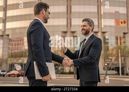 Foto von zwei Geschäftsleuten, die sich die Hände schütteln. Zwei Geschäftsleute schütteln sich die Hand. Stockfoto