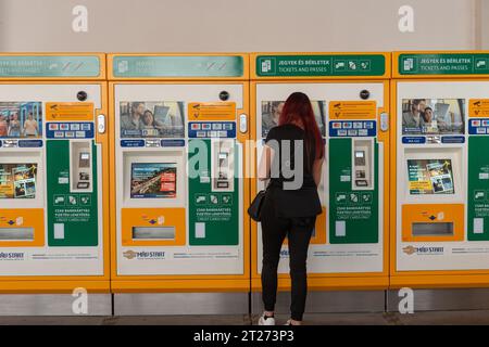 Budapest, Ungarn. 1. Oktober 2023 Eine Frau, die eine Zugfahrkarte an einem Automaten am Bahnhof Nyugati Palyaudvar in Budapest, Ungarn, kauft. Stockfoto