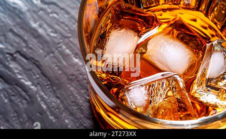 Whiskey wird in ein Kristallglas gegossen. Draufsicht. Goldene Flüssigkeit, die vor weißem Hintergrund in ein Glas gefüllt wird. Kopieren Sie den Bereich im rechten Teil des Fotos. Stockfoto