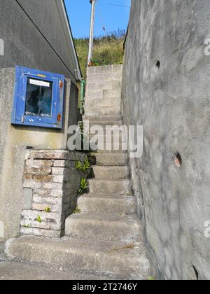 Treppen zwischen zwei Mauern in eine Gasse in Porthleven in Cornwall England Stockfoto