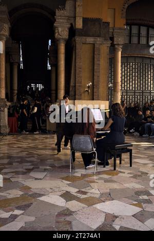 Mantova, Italien - September 2023 - Frau spielt Klavier auf der Veranda eines Palastes, während das Publikum zusieht Stockfoto