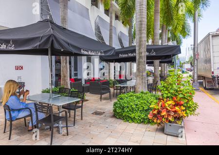 Blick auf die typische Restaurantszene am Straßenrand auf einer der Straßen von Miami. Eine einsame Besucherin sitzt mit ihrem Handy. Miami Beach. USA. Stockfoto