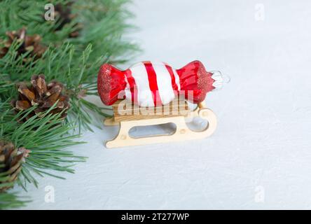 Weihnachtsdekorationen, Bonbonförmiges Weihnachtsspielzeug, festlicher winterblauer Hintergrund, Neujahrskomposition. Tannenzweige mit Tannenzapfen, Schlitten und W Stockfoto