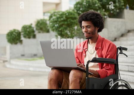 Junger schwarzer Mann mit Behinderung arbeitet als Freiberufler und beantwortet E-Mails auf Laptop Stockfoto
