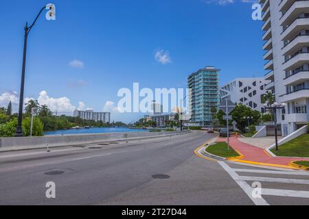 Wunderschöne urbane Landschaft von Miami Beach an sonnigen Sommertagen. Die Straße verläuft entlang des Flusses mit hohen modernen Gebäuden auf der anderen Seite. USA Stockfoto