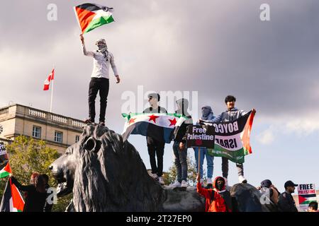 Pro-palästinensische Demonstranten weht die palästinensische Flagge auf der Löwenstatue an der Nelsons-Säule auf dem Trafalgar-Platz während des Freien palästinensermarsches in London. Stockfoto