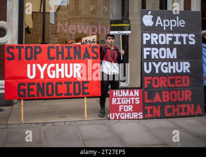 Aktivist für Uiguren steht mit großen Plakaten vor dem Apple Store in der Londons Regent Street. Oktober 2023. "Stoppt Chinas Völkermord an den Uiguren". Stockfoto