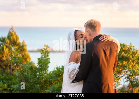 Glückliches Brautpaar umarmt sich vor dem Hintergrund einer Meereslandschaft Stockfoto