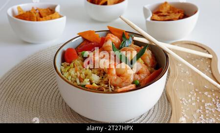 Schnelle und gesunde asiatische Mahlzeit aus gebratenem Reis, frischen Garnelen und Gemüse in einer Schüssel auf dem Tisch. Draufsicht, direkt über der Aufnahme Stockfoto