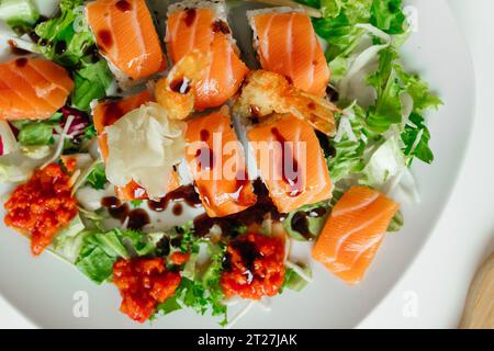 Blick von oben auf japanisches Sushi. Brötchen mit Thunfisch, Lachs, Garnelen, Krabben und Avocado. Blick von oben auf Regenbogenuramaki, Hosomaki und Nigiri mit Teriyaki-Sauce Stockfoto