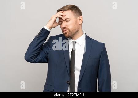 Müder, verwirrter, frustrierter Geschäftsmann im offiziellen Anzug mit unzufriedener Stirn Stockfoto