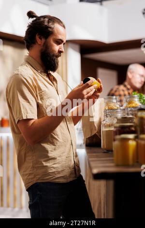 Ein Mann im Zero Waste Store nimmt sich Zeit, um Saft zu analysieren und sicherzustellen, dass er aus Bio-Früchten hergestellt wird. Kunden, die Lebensmittelartikel gründlich prüfen, sind in einem umweltverträglichen Supermarkt sicher Stockfoto