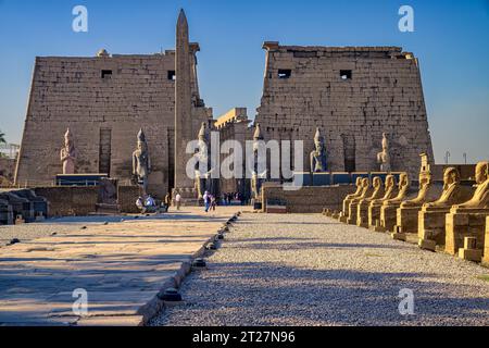 Die kolossalen Statuen von Ramses II. Und Obelisk am ersten Pylon des Tempels von Luxor, von der Sphinxstraße aus gesehen Stockfoto