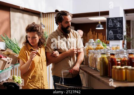 Green Living Paare, die in einem Null-Abfall-Supermarkt einkaufen, auf der Suche nach Bio-Lebensmitteln. Vegane Kunden, die sich auf den Winter vorbereiten, kaufen Vorratshandelsartikel in einem Laden in der Nachbarschaft Stockfoto