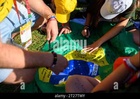 Pilger, die eine brasilianische Flagge als Andenken unterzeichnen. Die Eröffnungszeremonie der Weltjugendtage 2023 in Lissabon, Portugal. Stockfoto