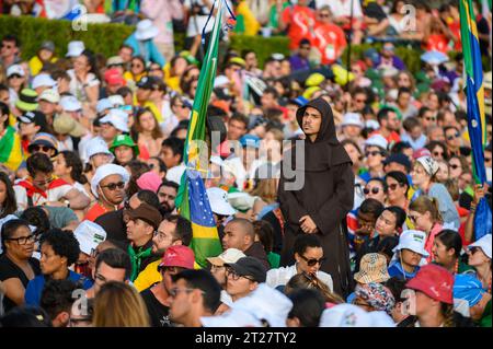 Ein Mönch, der bei der Eröffnungszeremonie der Weltjugendtage 2023 in Lissabon, Portugal, unter einer sitzenden Menge von Pilgern stand. Stockfoto