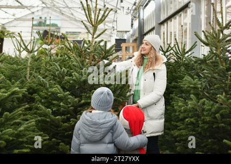 Mutter und Kinder kaufen einen Weihnachtsbaum auf dem Markt. Stockfoto