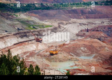 Hydraulikbagger und Kipplaster, die im Tagebau in Bergbau- und Verarbeitungsanlagen Erdbewegungsarbeiten durchführen. Stockfoto