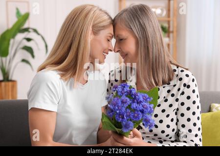 Glückliche reife Mutter und Tochter mit schönen Kornblumen zu Hause Stockfoto